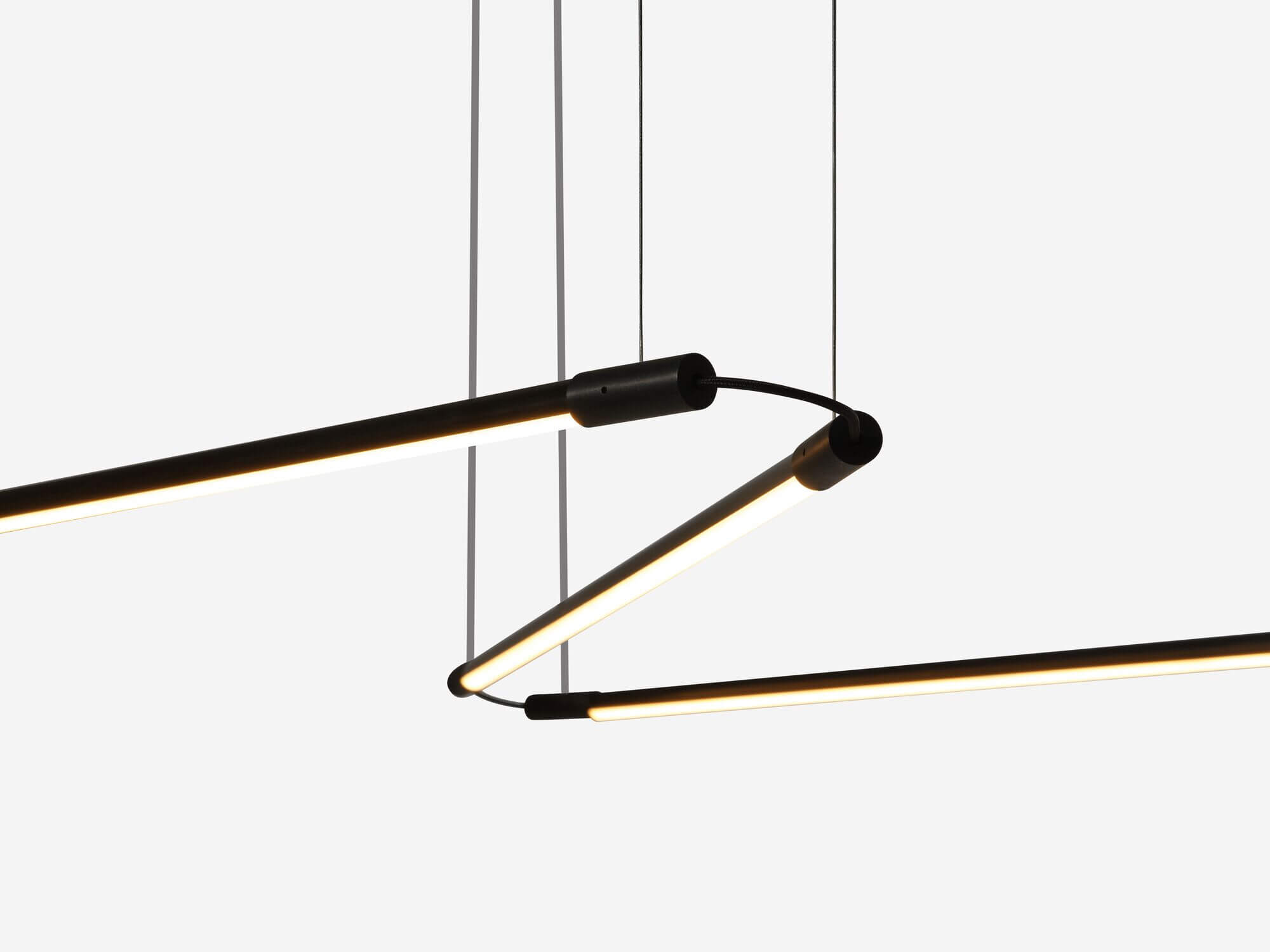 Detail view of curving slim black pendant lamp with light on